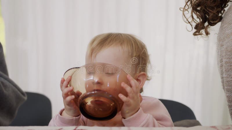 Mignon bébé mange une orange dans un bol en verre banque de vidéos