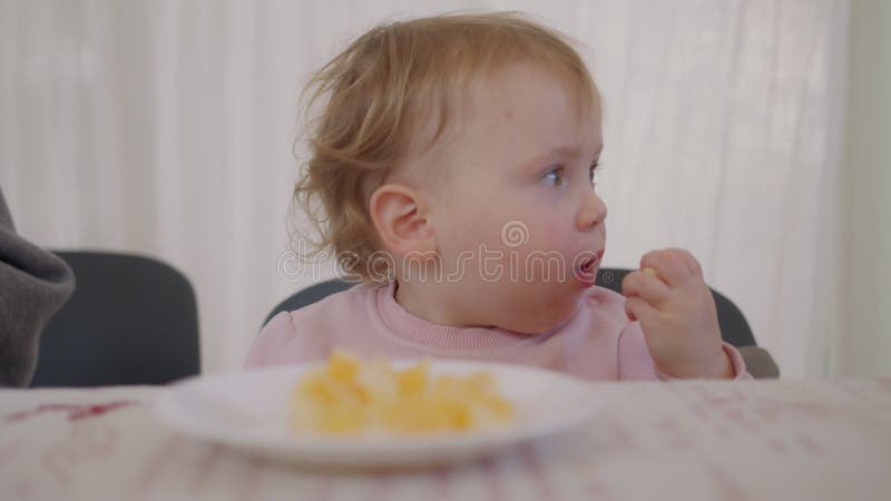 Mignon bébé mange une orange à côté d'une table clips vidéos
