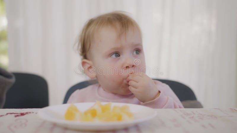 Mignon bébé mange une orange à côté d'une table clips vidéos