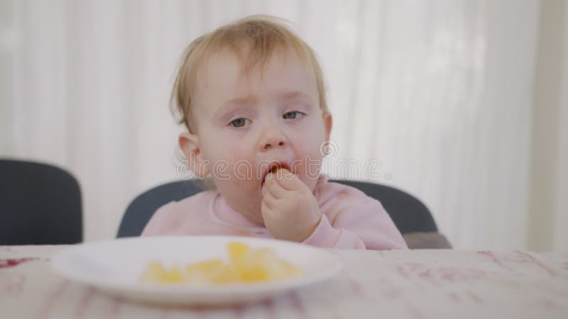 Mignon bébé mange une orange à côté d'une table banque de vidéos