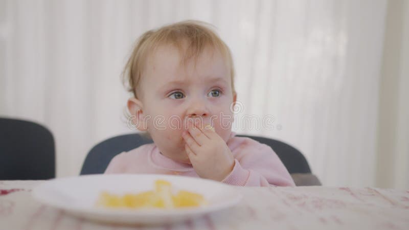 Mignon bébé mange une orange à côté d'une table clips vidéos