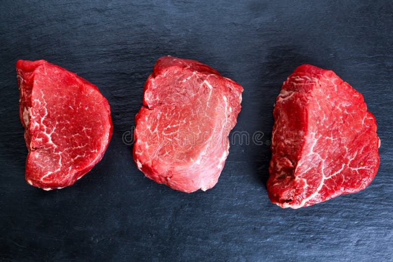 Mignon crudo fresco della bistecca di manzo sul fondo scuro blu del bordo, fotografie stock libere da diritti Mignon crudo fresco della bistecca di manzo sul fondo scuro blu del bordo, fotografie stock libere da diritti