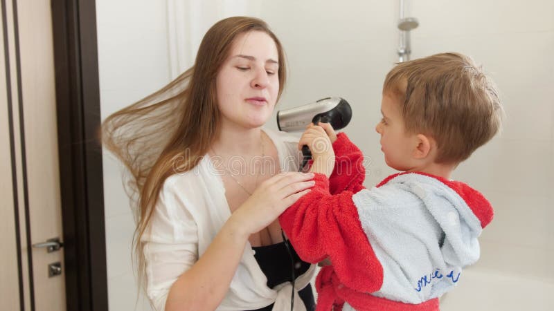 Le Garçon Blond Aux Cheveux Mouillés Est Drôle Séché Par Un Sèche-cheveux.