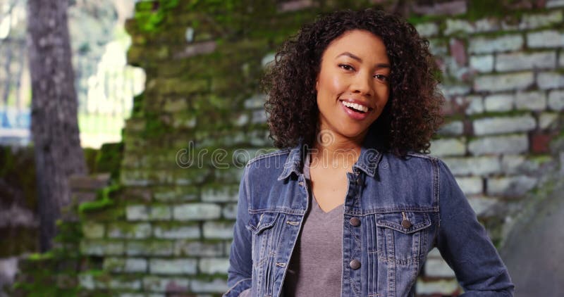 Mignonne femme africaine avec cheveux bouclés souriant à la caméra joyeusement dehors banque de vidéos