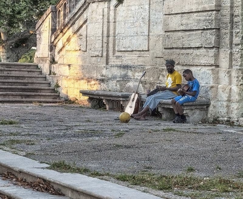 Migranter i Europa Fadern undervisar för att spela gitarrsvartbarnet på gatan i Montpellier, Frankrike fotografering för bildbyråer Migranter i Europa Fadern undervisar för att spela gitarrsvartbarnet på gatan i Montpellier, Frankrike fotografering för bildbyråer