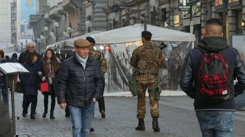 Milan, Italy- February 24, 2017 . Crowded Street. The pedestrian zone is patrolled by armed soldiers. Back view .