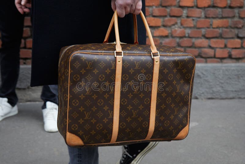 Man with brown Louis Vuitton backpack and black padded jacket