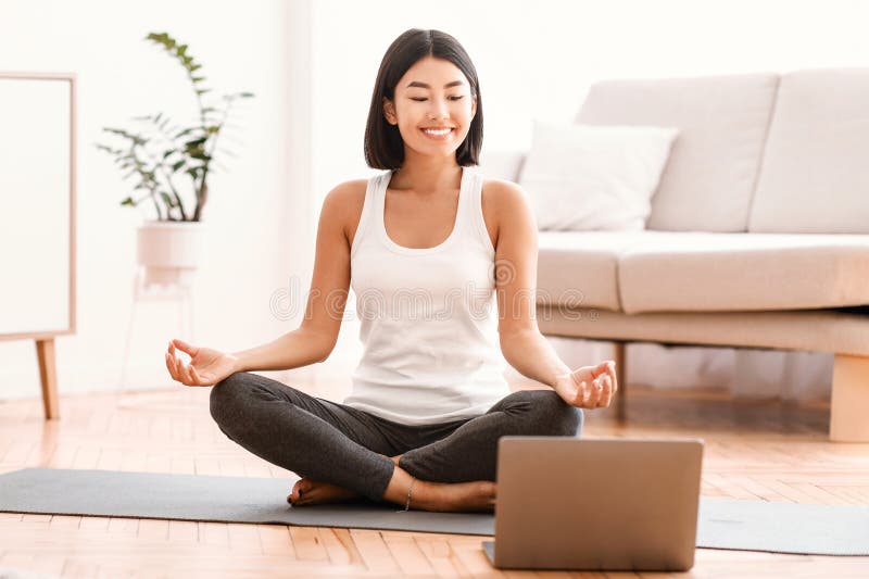 Milenesa meditando con entrenadora en línea en una laptop fotografía de archivo libre de regalías