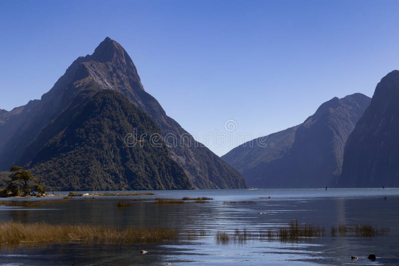 Milford Sound Nya Zeeland - Mitremaximumet är den iconic gränsmärket av Milford Sound i den Fiordland nationalparken Sommarmiddag royaltyfria foton Milford Sound Nya Zeeland - Mitremaximumet är den iconic gränsmärket av Milford Sound i den Fiordland nationalparken Sommarmiddag royaltyfria foton