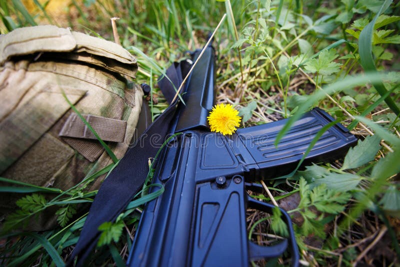 Militaire helm, geweer en een bloem in gras dichte omhooggaand royalty-vrije stock foto's Militaire helm, geweer en een bloem in gras dichte omhooggaand royalty-vrije stock foto's