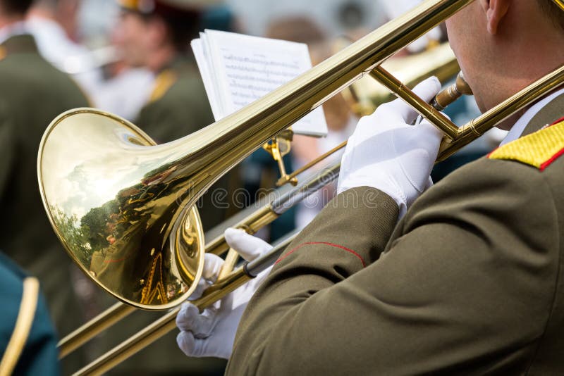 Military musician blowing gold trombones. Military musician blowing gold trombones