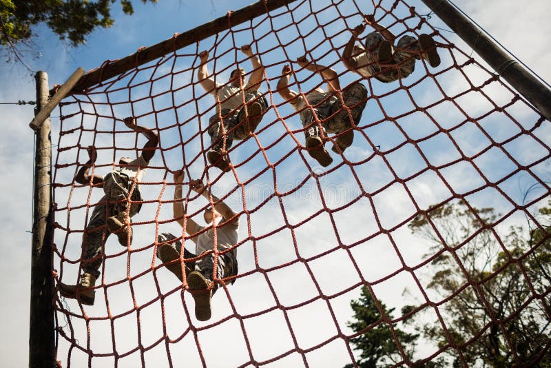 Military soldiers climbing rope during obstacle course