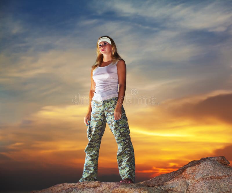 Military woman staying aon the mountain peak at sunrise time