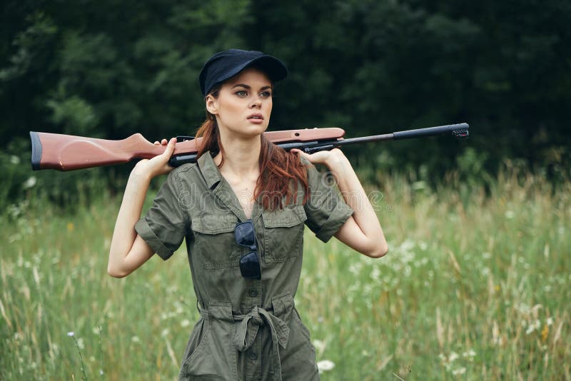 Military woman Holding a weapon behind his back black cap hunting lifestyle green overalls