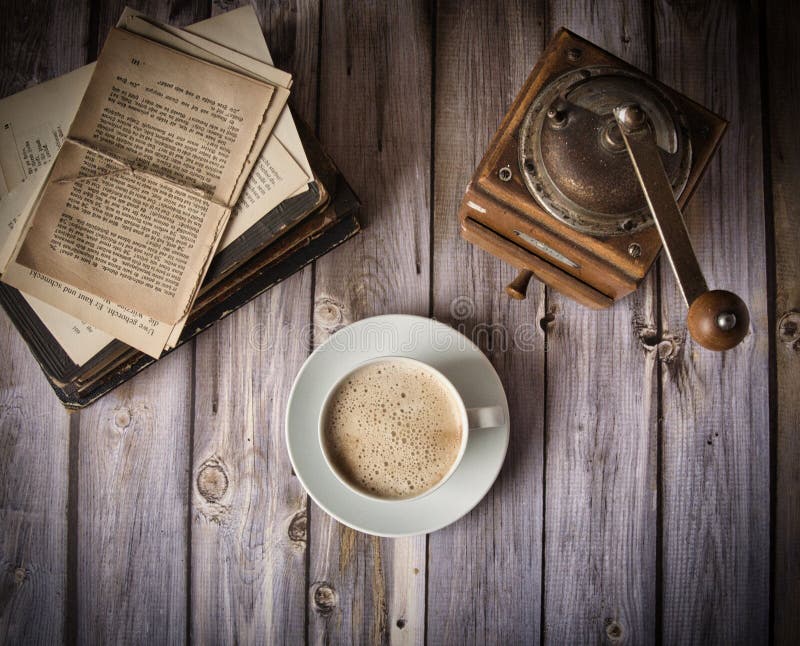 Milk coffee in front of old books and an old coffee mill