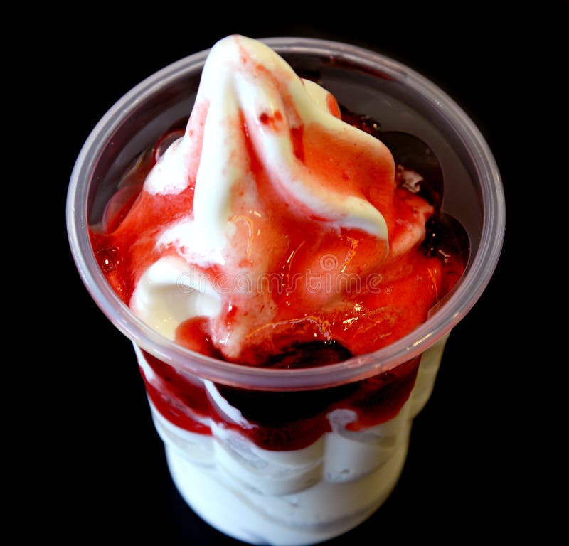 Milk icecream with strawberry sauce in takeaway cup on black background