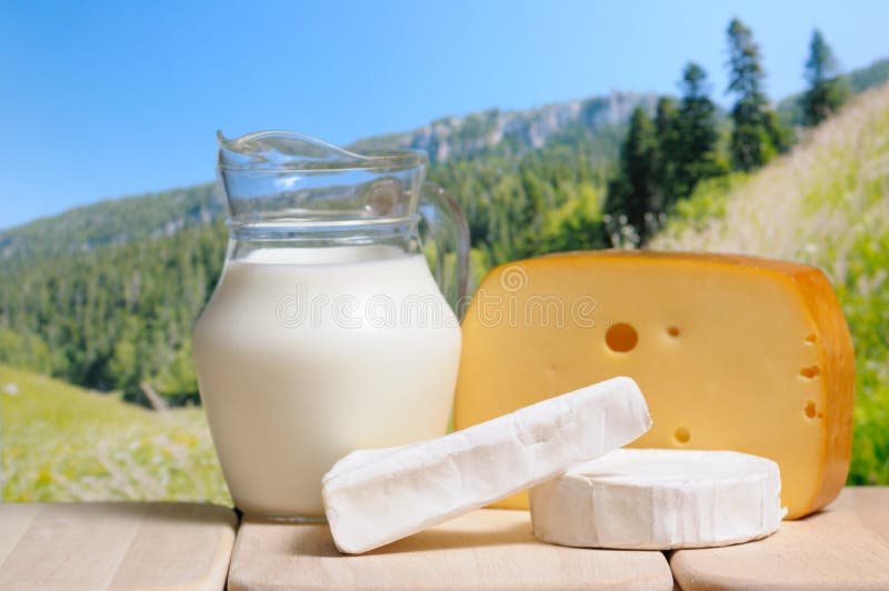 Milk jug and cheese against a mountains in background. Mountain milk stock images, royalty-free photos and pictures