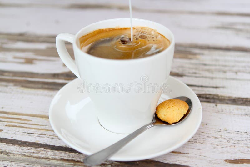 Milk pouring into fresh coffee stock photography