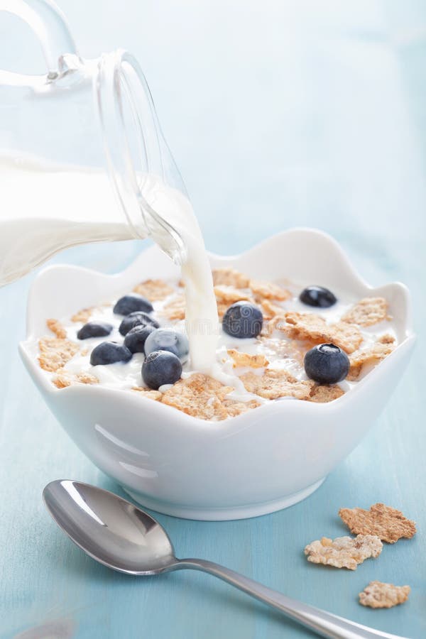 Milk pouring onto cornflakes with blueberry