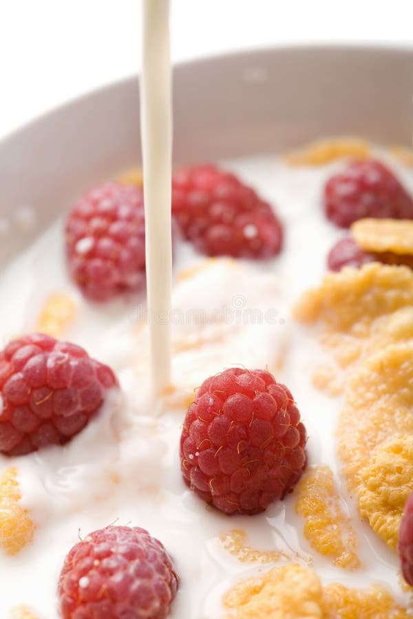Milk pouring onto muesli with raspberry