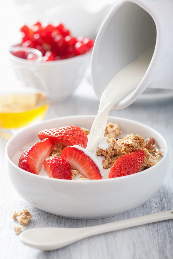 Milk pouring over granola strawberry breakfast stock photo