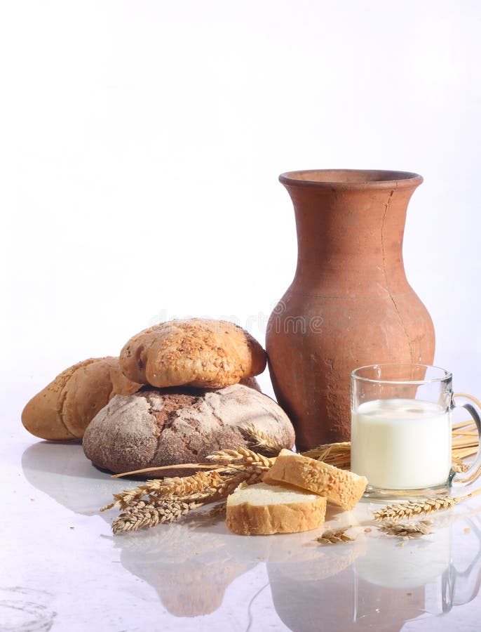 Milk in a transparent mug and fresh bread on a white background