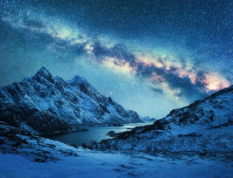 Milky Way over snow covered mountains and sea coast at night