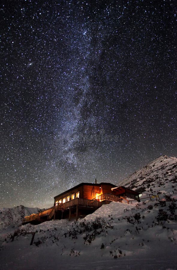 Milky way over winter mountain landscape with cottage, Slovakia