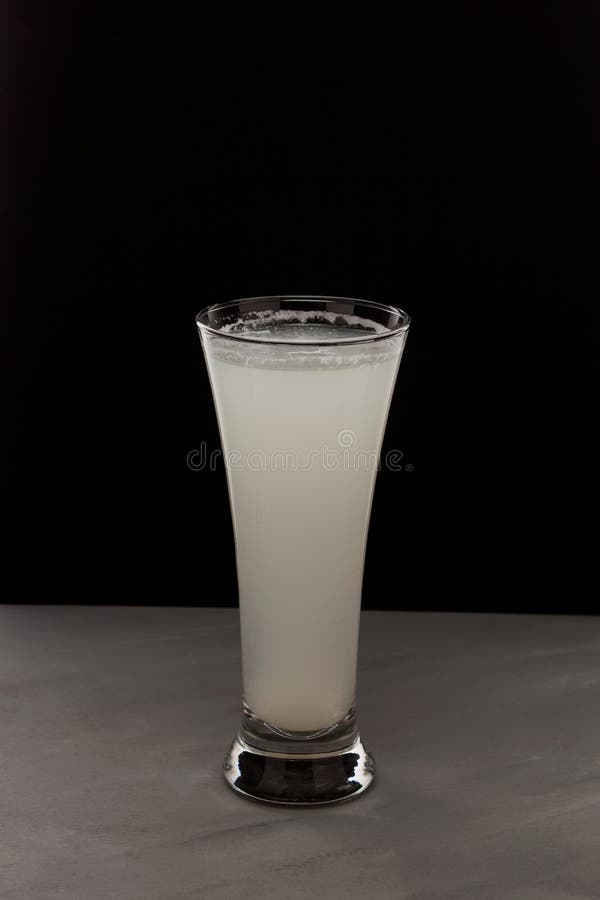 Milky white drink in clear glass. Alcoholic or non alcoholic drink on dark background with copy space