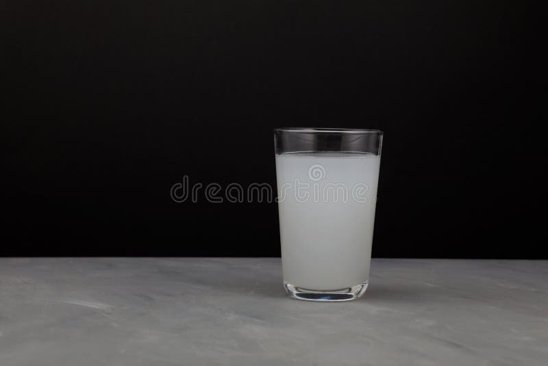 Milky white drink in clear glass on dark background with copy space