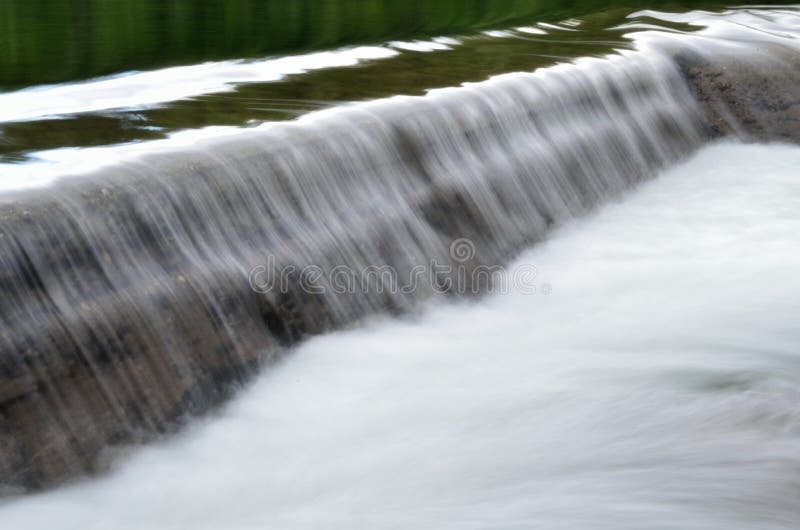 Milky white river flood torrent over concrete barrier