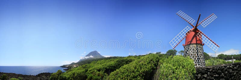 A typical Portugal old mill on Azores / Pico island. Around vineyards with the Atlantic Ocean on the horizont and the Pico mount the background with 2351m high. A typical Portugal old mill on Azores / Pico island. Around vineyards with the Atlantic Ocean on the horizont and the Pico mount the background with 2351m high.