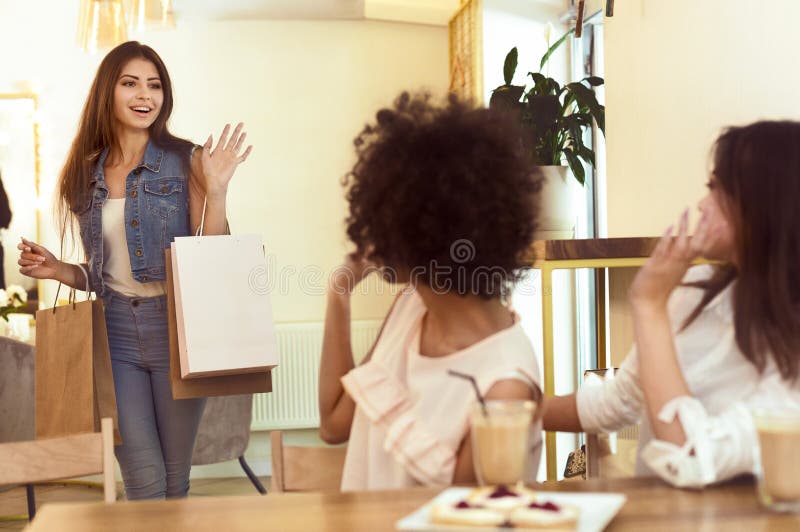Millennial flicka att möta hennes vänner i kafé, når att ha shoppat dag royaltyfri fotografi