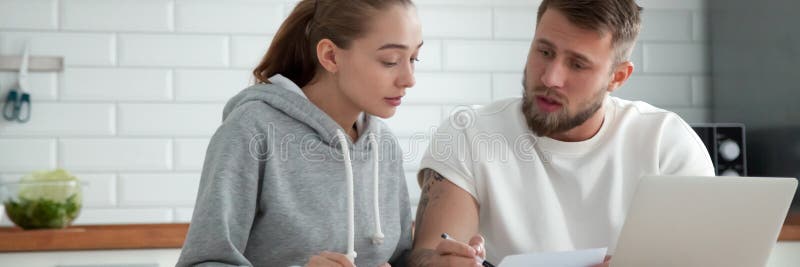Millennial pary małżeńskiej obsiadanie przy stołowymi czytelniczymi sprawdza pożyczka dokumentami zdjęcia stock Millennial pary małżeńskiej obsiadanie przy stołowymi czytelniczymi sprawdza pożyczka dokumentami zdjęcia stock