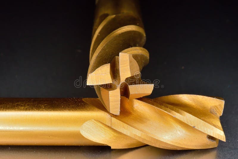 Spiral 4 flute titanium nitride (TiN) coated end mill cutters for profiling in a vertical milling machine shot with a dark background. Spiral 4 flute titanium nitride (TiN) coated end mill cutters for profiling in a vertical milling machine shot with a dark background