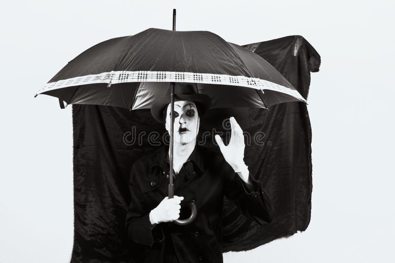 Mime en un sombrero que sostiene un paraguas en su mano imágenes de archivo libres de regalías Mime en un sombrero que sostiene un paraguas en su mano imágenes de archivo libres de regalías