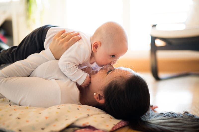 Mime a mentira en el piso que detiene a su hijo lindo del bebé fotos de archivo Mime a mentira en el piso que detiene a su hijo lindo del bebé fotos de archivo