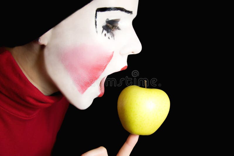 Mime biting an apple on a black background. Mime biting an apple on a black background