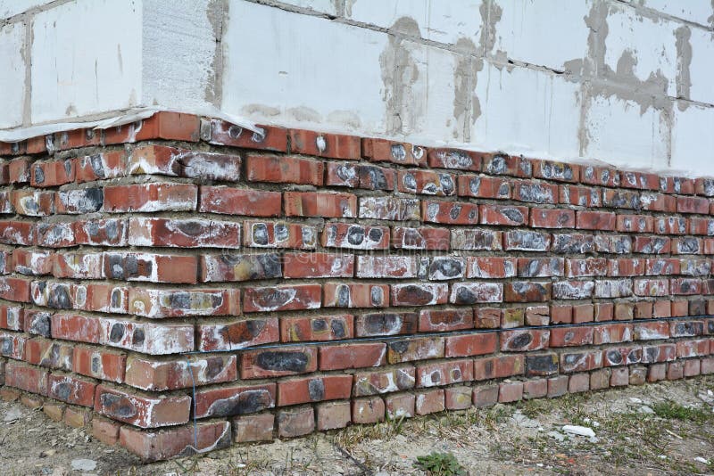 Mineral efflorescence on brick house foundation wall. Efflorescence salt as an indicator of moisture problems in house building