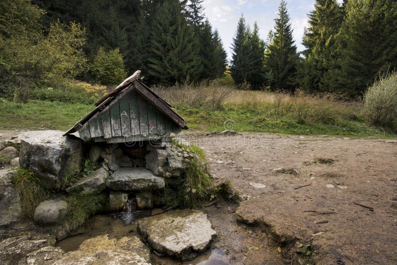 Minerální pramen krytý malou dřevěnou stříškou v létě