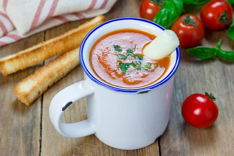 Minestra casalinga del basilico del pomodoro nella tazza, servita con il bastone del formaggio della mozzarella fotografie stock Minestra casalinga del basilico del pomodoro nella tazza, servita con il bastone del formaggio della mozzarella fotografie stock