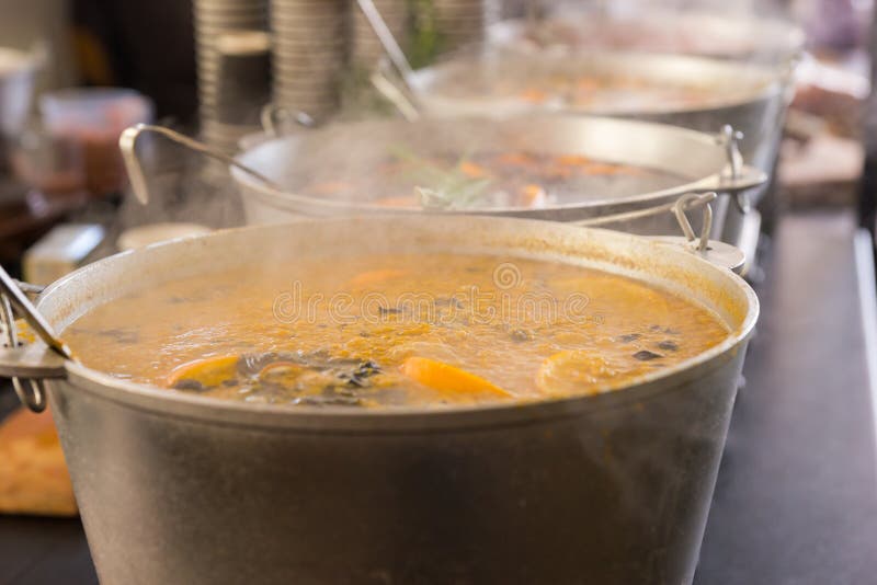 Spicy soup in large cauldrons with ladle inside at outdoor food festival. Food and beverages concept. Spicy soup in large cauldrons with ladle inside at outdoor food festival. Food and beverages concept