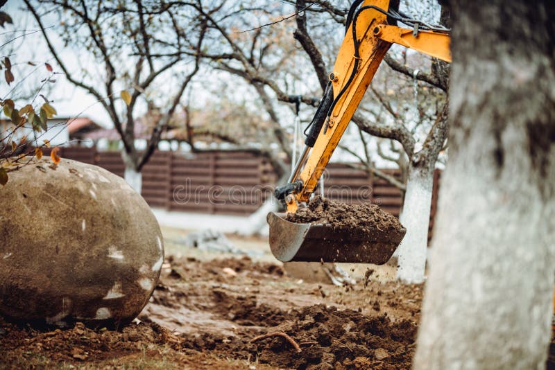 Крупный план ковша мини-экскаватора, перемещающего землю и выполняющего работы по ландшафтному дизайну стоковое фото rf