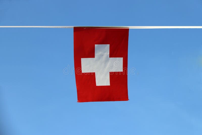 Mini bandera del carril de la tela de Suiza, es consiste en una bandera roja con una cruz blanca en el centro, colgando en el pañ foto de archivo Mini bandera del carril de la tela de Suiza, es consiste en una bandera roja con una cruz blanca en el centro, colgando en el pañ foto de archivo