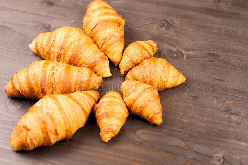 Mini e maxi croissant che si trovano sulla tavola di legno immagine stock Mini e maxi croissant che si trovano sulla tavola di legno immagine stock