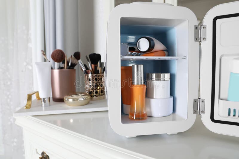 Mini Fridge with Cosmetic Products on White Vanity Table Stock Photo