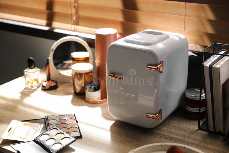 Mini Fridge with Cosmetic Products on White Vanity Table Stock