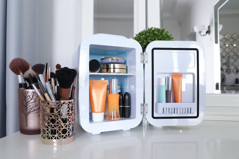 Mini Frigo Avec Produits Cosmétiques Sur Table Blanche Photo stock