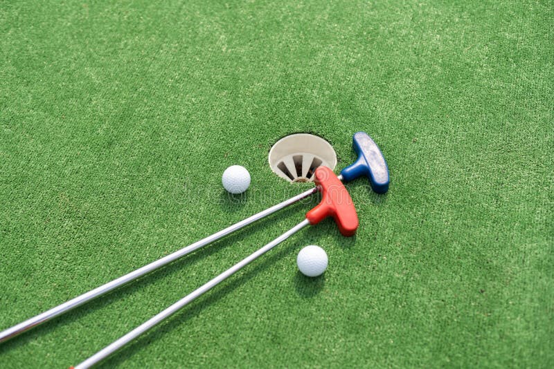 Minigolf Clubs and Balls of Different Colors Laid on Artificial Grass