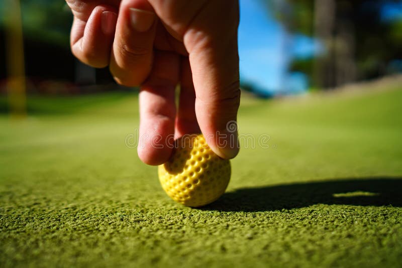 Mini Golf yellow ball on green grass at sunset